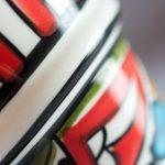 Close-up of handpainted geometric pattern on ceramic espresso cup showing red, green, and blue details