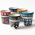 Five handpainted ceramic espresso cups in assorted colors showing red, blue, yellow, and green patterns