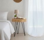 Natural wood side table as bedroom nightstand with reading lamp and succulent plant