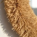 Close-up detail of handwoven straw mirror showing thick fluffy natural raffia texture and artisan craftsmanship