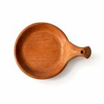 Single terracotta serving dish with carved handle showing handmade texture and warm clay color