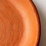 Close-up of handmade terracotta baking dish surface showing natural clay texture and wheel marks