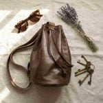 Brown leather bucket bag flat lay with sunglasses lavender and vintage keys