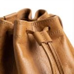Close-up of tan leather bucket bag drawstring closure and stitching detail