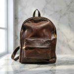 Genuine leather backpack front view on marble surface with gold zipper details