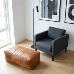 Rectangular Moroccan leather ottoman in light brown placed in a modern minimalist living room corner.