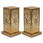 Pair of hand-engraved perforated brass table lamps with geometric floral patterns glowing warmly against white background