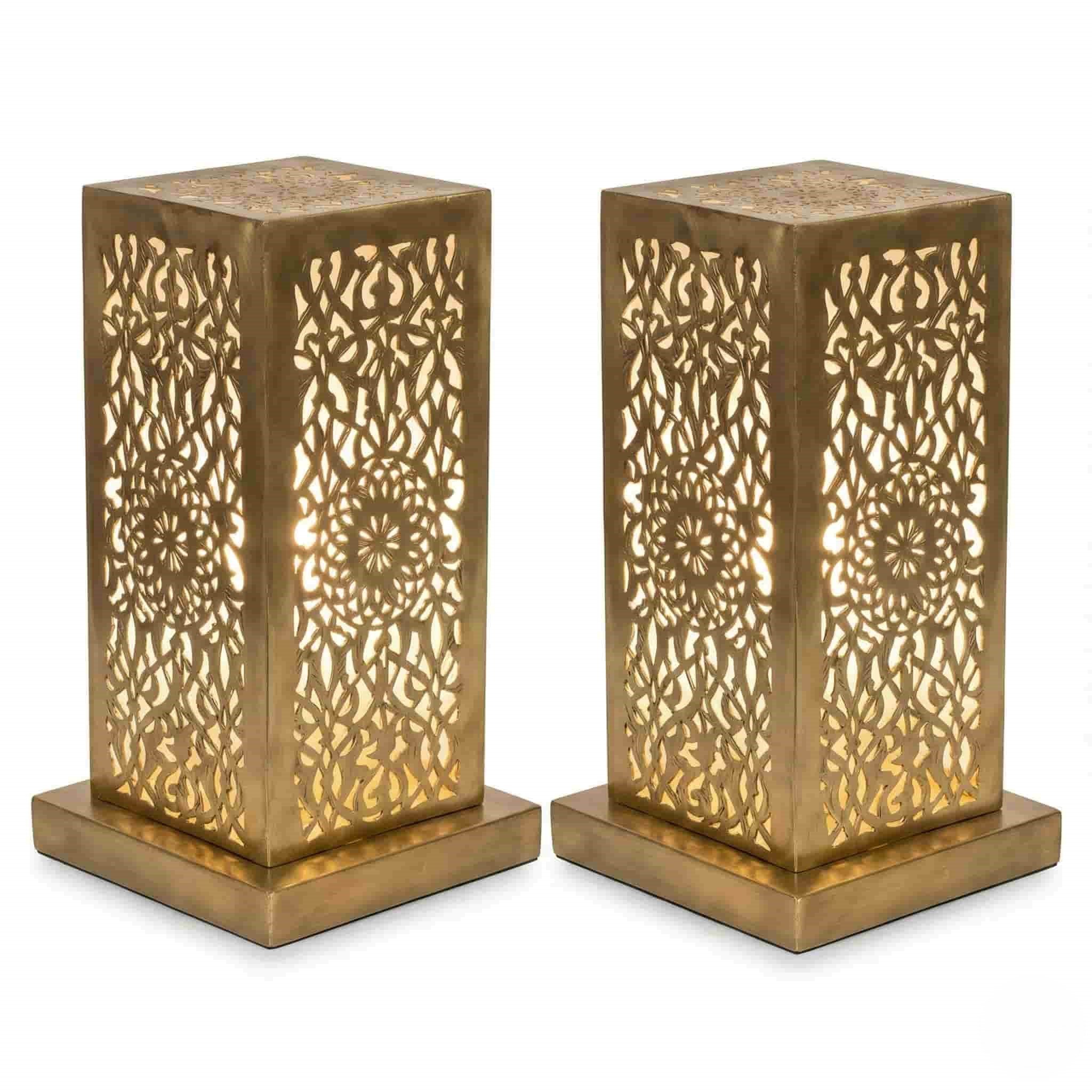 brass table lamp (1) Pair of hand-engraved perforated brass table lamps with geometric floral patterns glowing warmly against white background