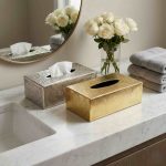 Brass tissue box covers in silver engraved and gold hammered finishes on marble bathroom vanity with roses