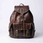 Genuine leather travel backpack front view with brass buckles and drawstring closure