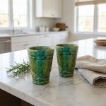 Two green ceramic mugs on white marble kitchen counter in contemporary minimalist setting