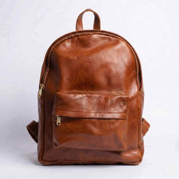 Minimalist leather backpack in tan brown featuring a front zippered pocket and brass hardware, handcrafted from full-grain Moroccan leather