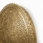 Detail view of brass filigree wall lamp showing scalloped lace-like edge and construction quality