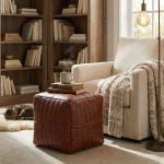 Leather cube ottoman used as side table with books and coffee mug in reading nook