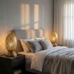 Pair of brass oval table lamps as bedside lighting creating decorative shadow patterns on gray bedroom walls