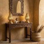 Pair of brass pear table lamps flanking ornate mirror on carved wooden console table in bohemian entryway