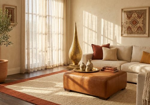 Sophisticated Moroccan-modern living room featuring brass floor lamp, cognac leather ottoman, and terracotta border wool rug in warm afternoon light