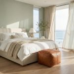 Braided leather square ottoman at foot of bed in coastal bedroom with ocean view