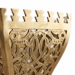 Close-up of hand-engraved brass filigree detailing and castellated crown edge on artisan wall sconce