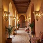 Row of brass filigree wall sconces illuminating arched corridor of Moroccan riad hotel
