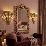 Pair of brass filigree wall sconces flanking ornate gold mirror in romantic bedroom setting