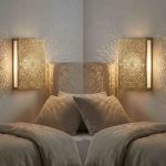 Pair of brass mandala wall lights flanking bed headboard casting radial shadow patterns across bedroom walls