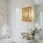 Brass mandala wall light mounted above marble bathroom vanity projecting geometric light patterns