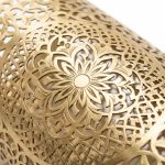 Close-up of hand-engraved brass filigree detail on Moroccan wall lamp showing star medallion