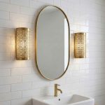 Pair of Moroccan filigree brass wall lights flanking oval mirror above bathroom vanity
