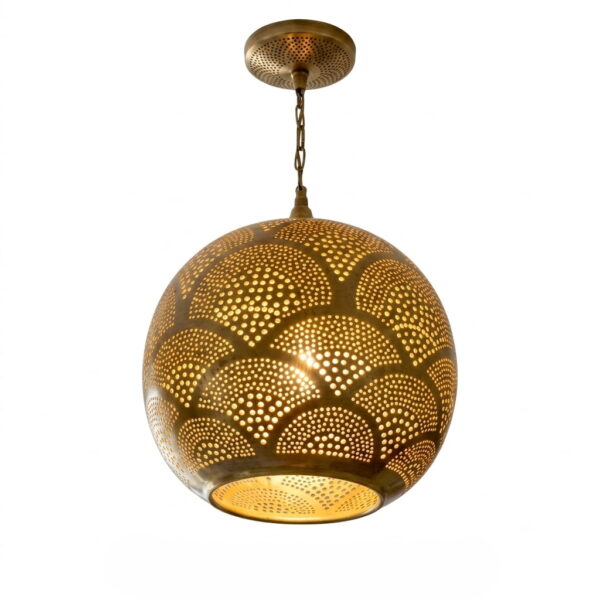 Moroccan brass pendant light lit, pierced fish scale globe glowing warm gold on white background