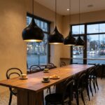 Row of black and gold teardrop pendant lights over a café communal table