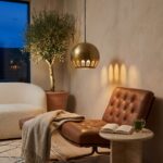Hammered brass globe pendant casting arched light shadows above a leather lounge chair