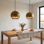 Pair of hammered brass globe pendant lights above an oak dining table