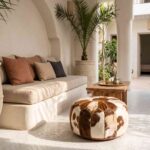 Brown and white cowhide pouf in a riad courtyard beside a built-in sofa and a mint tea tray
