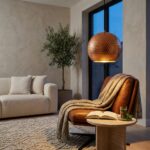 Copper globe pendant light glowing above a leather lounge chair at dusk