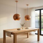Pair of copper globe pendant lights hanging over an oak dining table