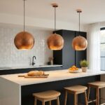 Three hammered copper globe pendant lights over a white kitchen island