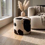 Black and white cowhide ottoman beside a boucle sofa and pampas grass on an oak floor