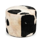 Black and white cowhide ottoman, round hair-on-hide drum pouf with leather piping, on white background
