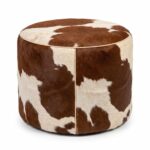 Brown and white cowhide ottoman, round hair-on-hide drum pouf with leather piping, on white background
