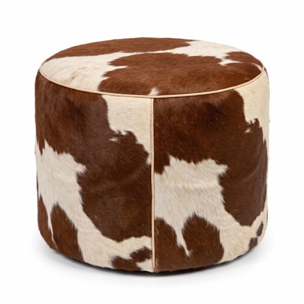 Brown and white cowhide ottoman, round hair-on-hide drum pouf with leather piping, on white background