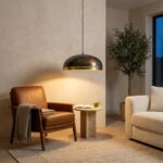 Patinated copper dome pendant light glowing above a leather armchair and side table