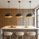 Three hammered copper dome pendant lights with gold leaf interiors over a marble kitchen island