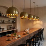 Row of hammered brass globe pendant lights over a café bar counter