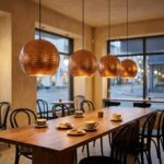 Row of hammered copper globe pendants glowing over a café table