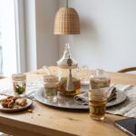 Moroccan glass tea set on a silver tray on an oak dining table with mint tea and chebakia