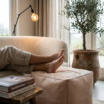 Natural undyed leather pouf used as a footrest in front of a cream bouclé sofa