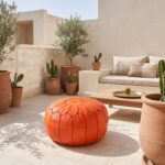 Orange leather pouf on a sunlit rooftop terrace with olive trees, terracotta pots and a brass tea tray