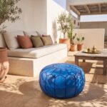Royal blue leather pouf on a rooftop terrace beside a built-in sofa, olive trees and a mint tea tray