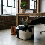 Black and white cowhide pouf used as a footrest under a wooden desk